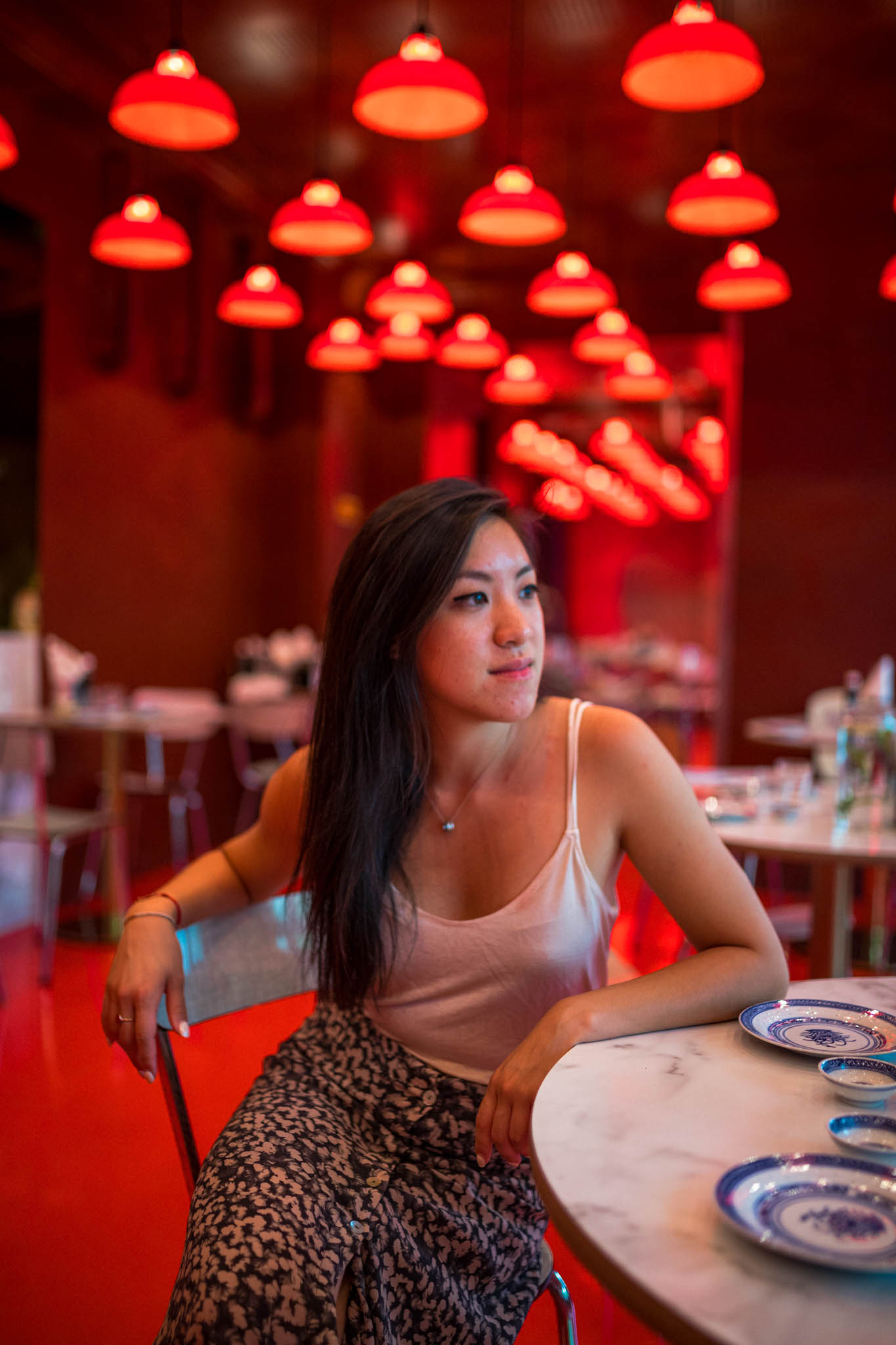 Céline Chung assise sur une chaise avec des luminaires rouges en fond