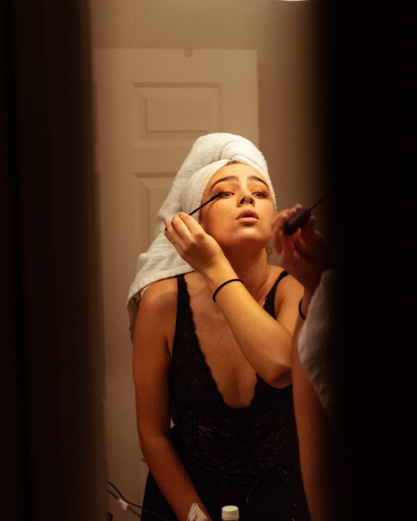 Photographie d'une femme avec une serviette sur les cheveux se mettant du mascara