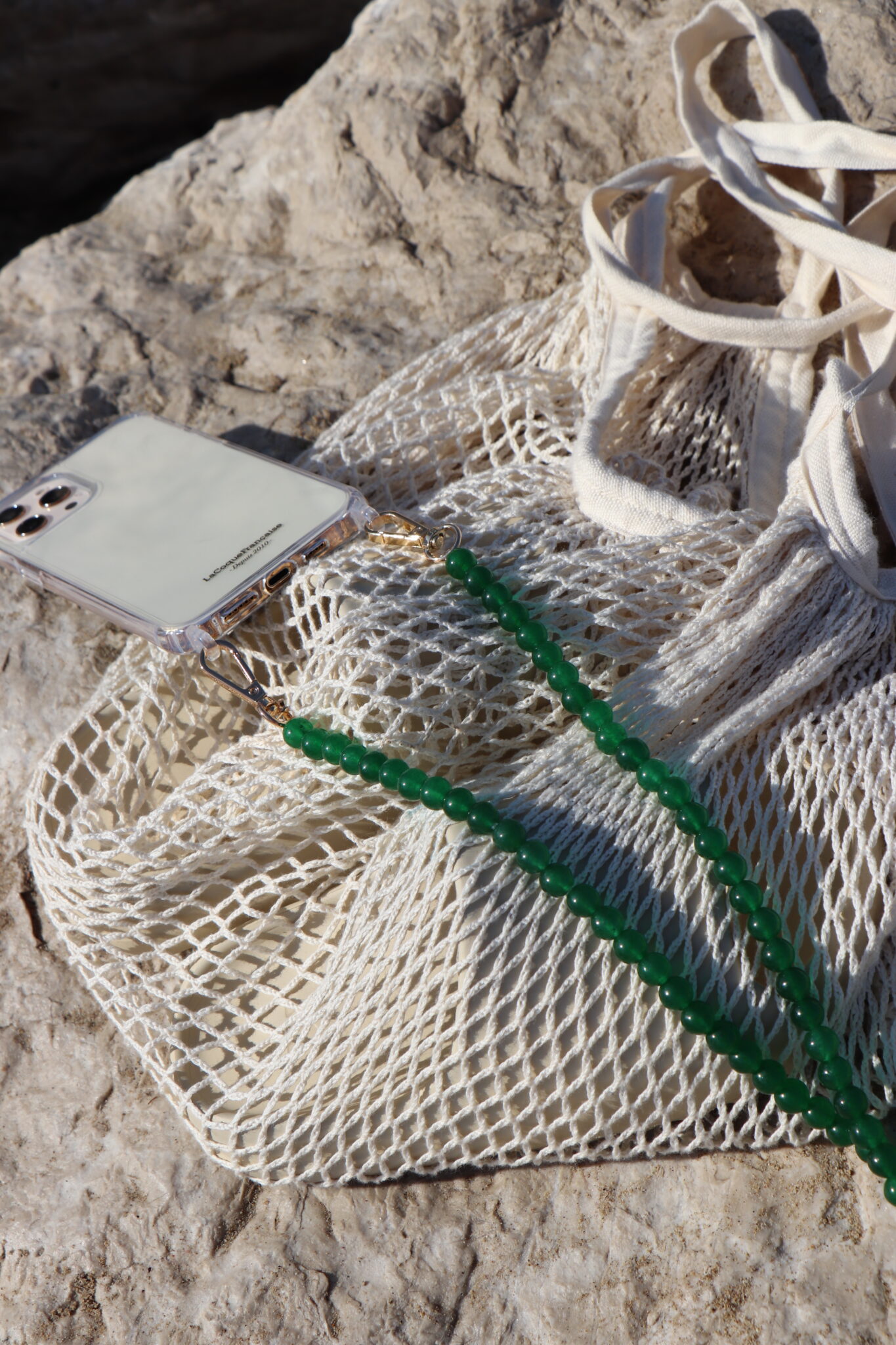 Chaîne de téléphone colorée posée sur un sac filet dans le sable