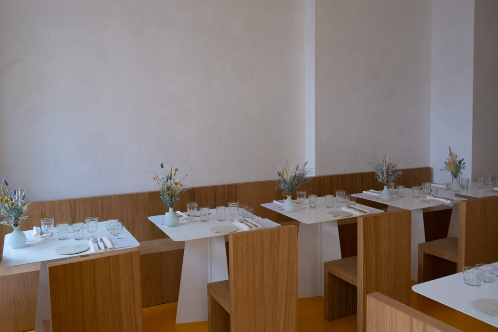 Intérieur de la salle de Rhézome avec des chaises en bois et tables blanches